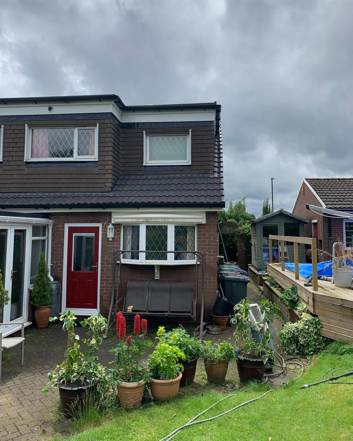 Rear of a brick family home with new tiling, red back door, decking and patio
