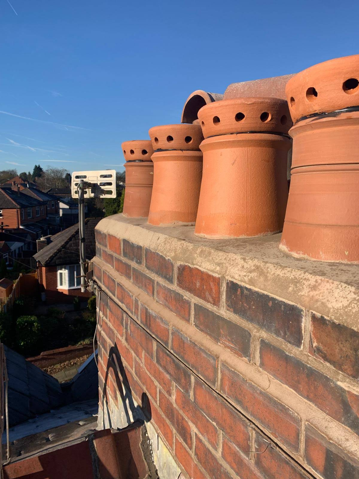 Brick chimney stack with newly seated terracotta vented pots and fresh cement flaunching